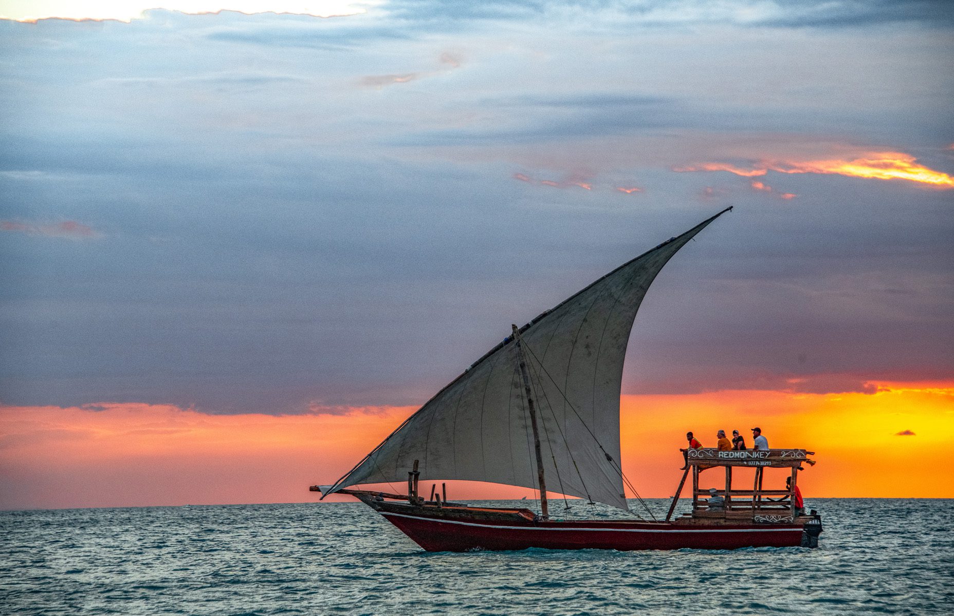Traditional wooden dhow sailing at sunset off the coast of Zanzibar, Tanzania