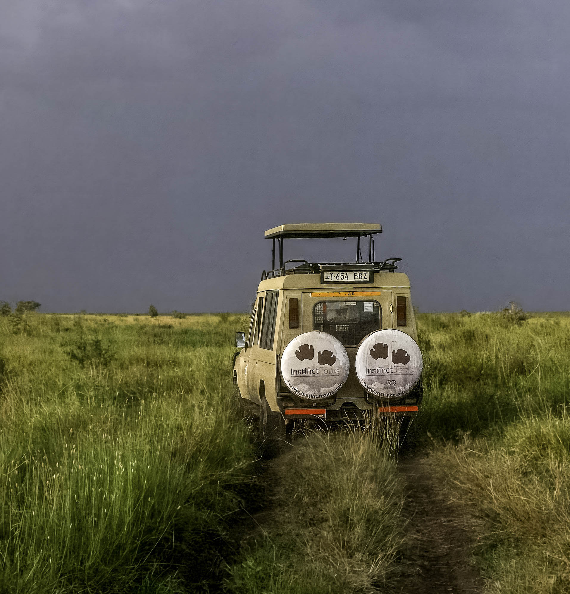 Instinct Tours Land Cruiser on evening safari drive across the Serengeti under darkening skies
